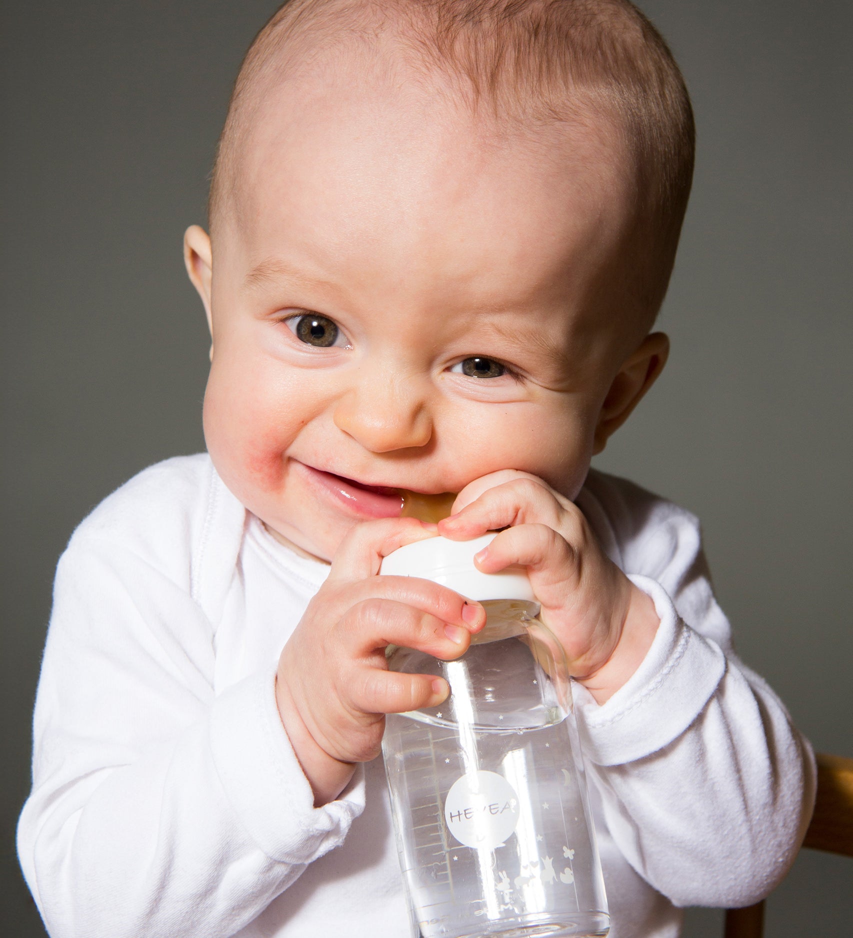 Baby biting down on a 100% natural rubber bottle nipple by HEVEA.