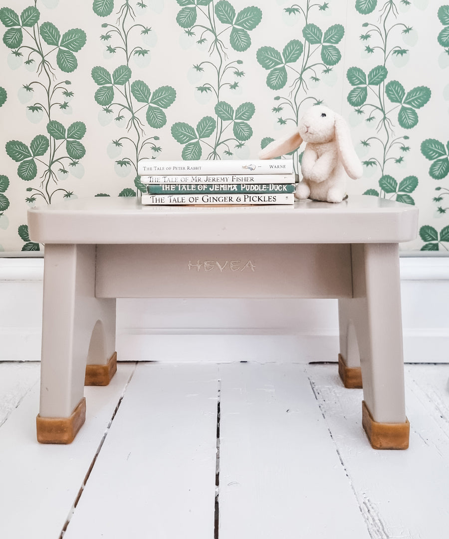 Hevea Rubberwood Step Stool in pink with a stack of children's books on the top and a toy rabbit.