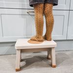 Child in yellow tights stood on a Hevea Rubberwood Step Stool at a kitchen counter. 