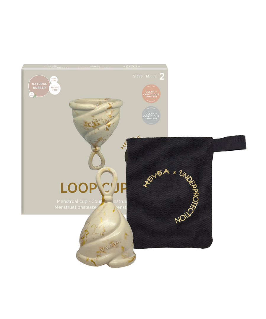 Hevea LOOP menstrual cup in cream, in front of its box with a black cotton storage bag.