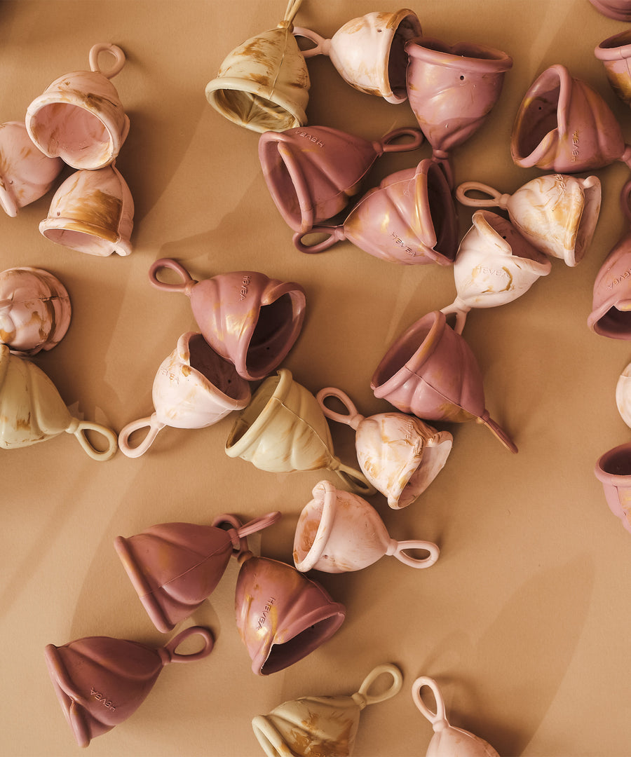 A collection of different sized LOOP menstrual cups in pink and cream.