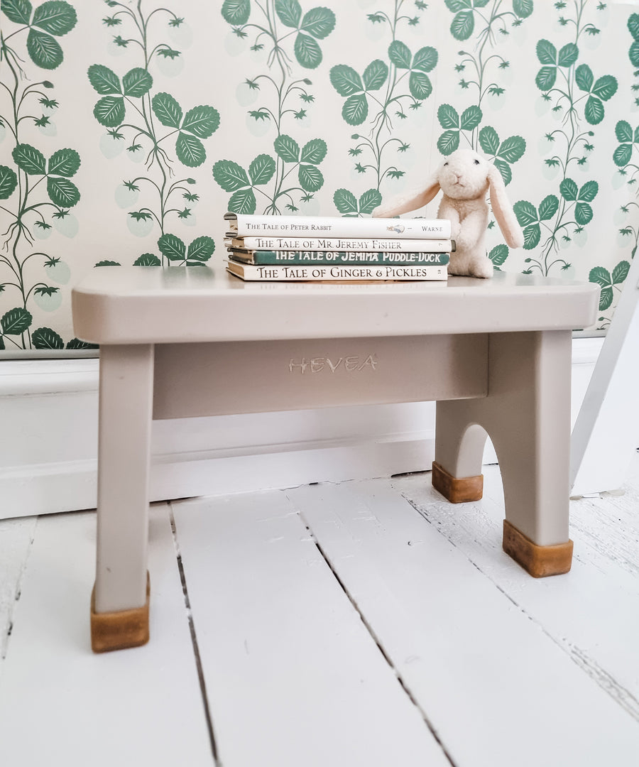 Hevea Rubberwood Step Stool in pink with a stack of children's books on the top and a toy rabbit.