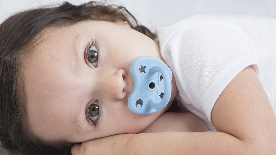 A baby with a blue pacifier / dummy from Hevea