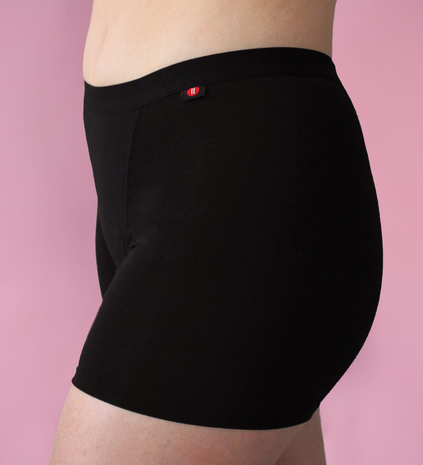 Hey Girls My Period Shorts from the side, in Black on a pink background