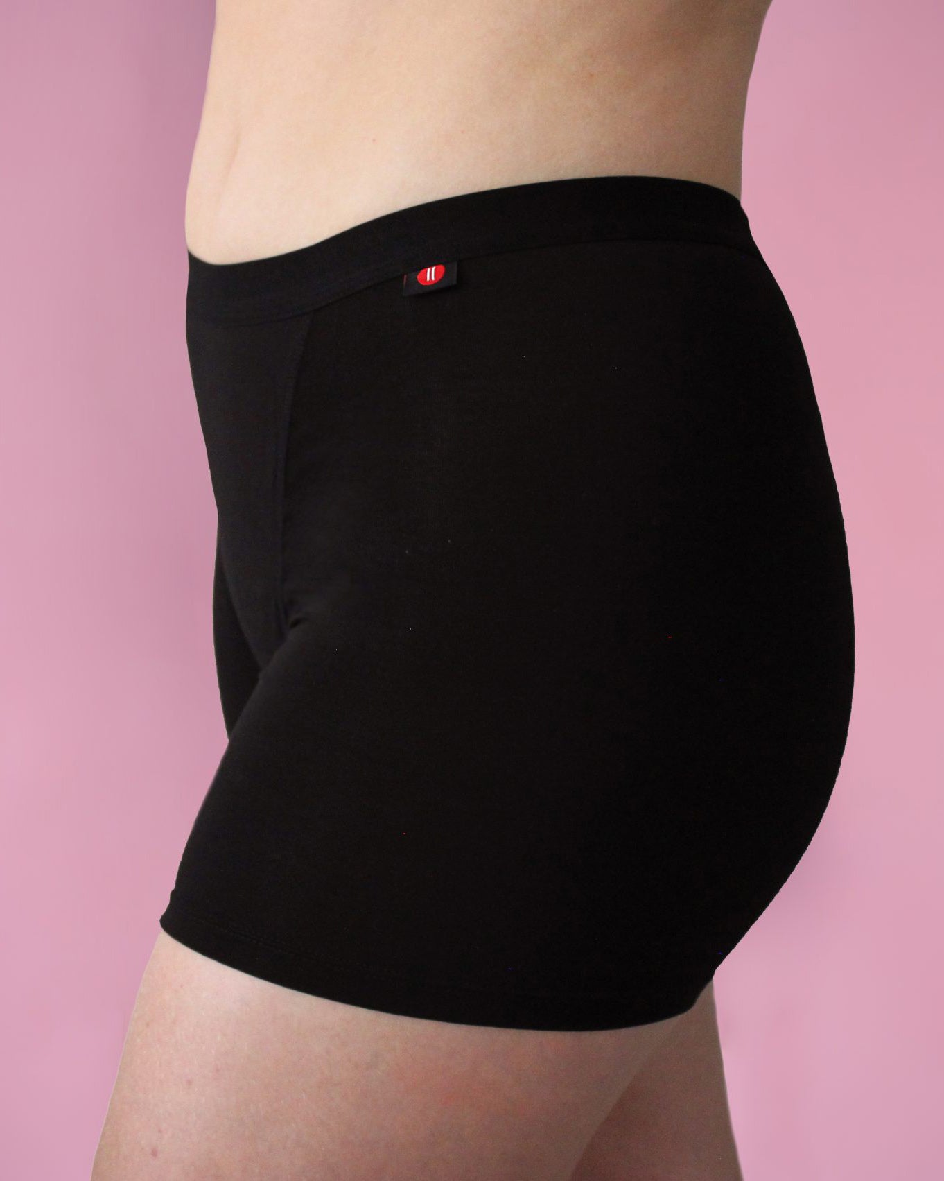 Hey Girls My Period Shorts from the side, in Black on a pink background