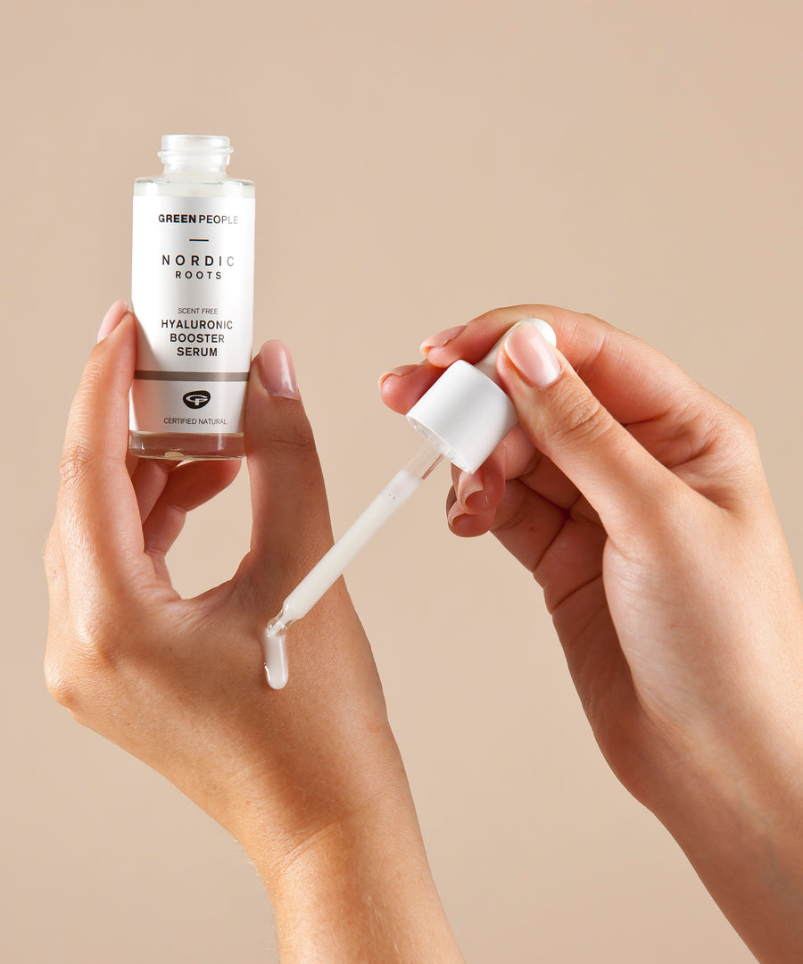 A person applying the Green People Nordic Roots Hyaluronic Booster Serum onto their hand to show the silky texture and white colour of the serum. 