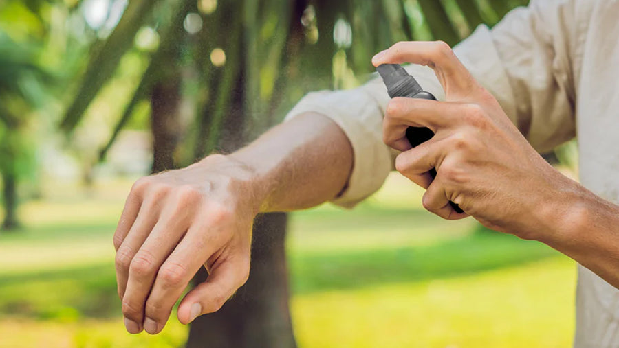 A person spraying Incognito bug and mosquito repellent spray onto their arms