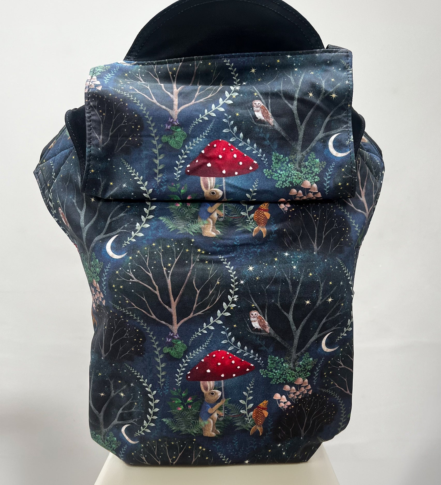 Integra Mr Rabbit Baby Carrier. Mr Rabbit is a whimsical illustrated print in soft organic cotton featuring a rabbit with a red mushroom umbrella taking a pet goldfish for a nighttime walk on an inky black background.