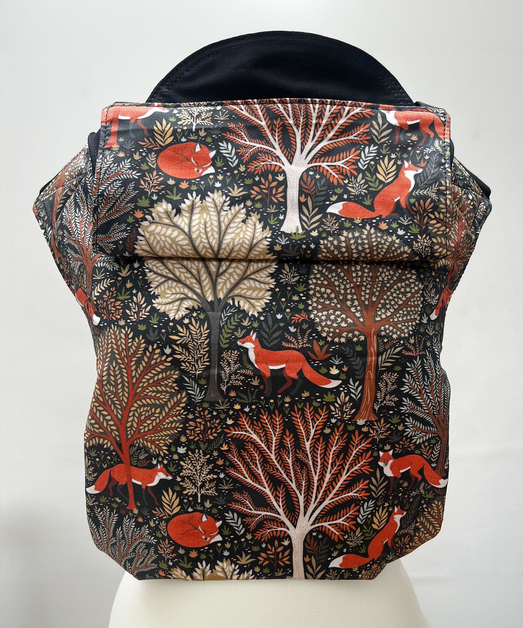 Integra Baby Carrier - Woodland Fox. Woodland Fox is a beautifully illustrated print in soft organic cotton featuring woodland trees in autumnal tones and red foxes on a black background.