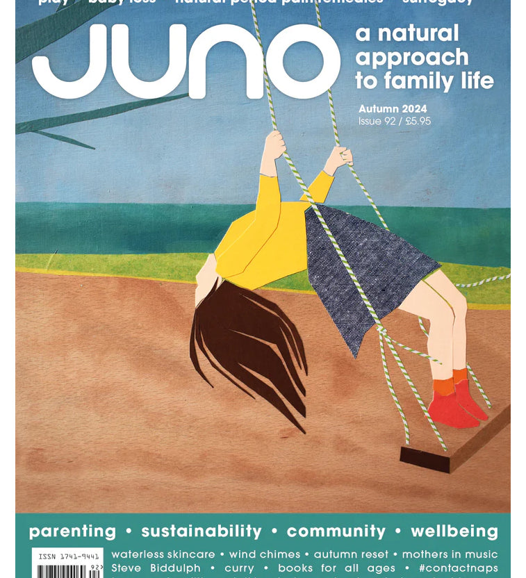 Juno Magazine Autumn 2024 Issue 92 shows a drawing of a person bending backwards whilst swinging on a swing. The person has brown hair, a yellow top, blue skirt, orange socks and red ankle boots. The front cover reads "Juno a natural approach to family life".