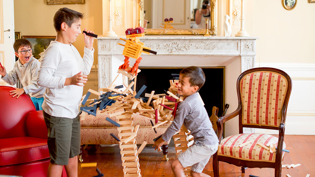 Children playing with KAPLA wooden toys as they fall off balance to the ground