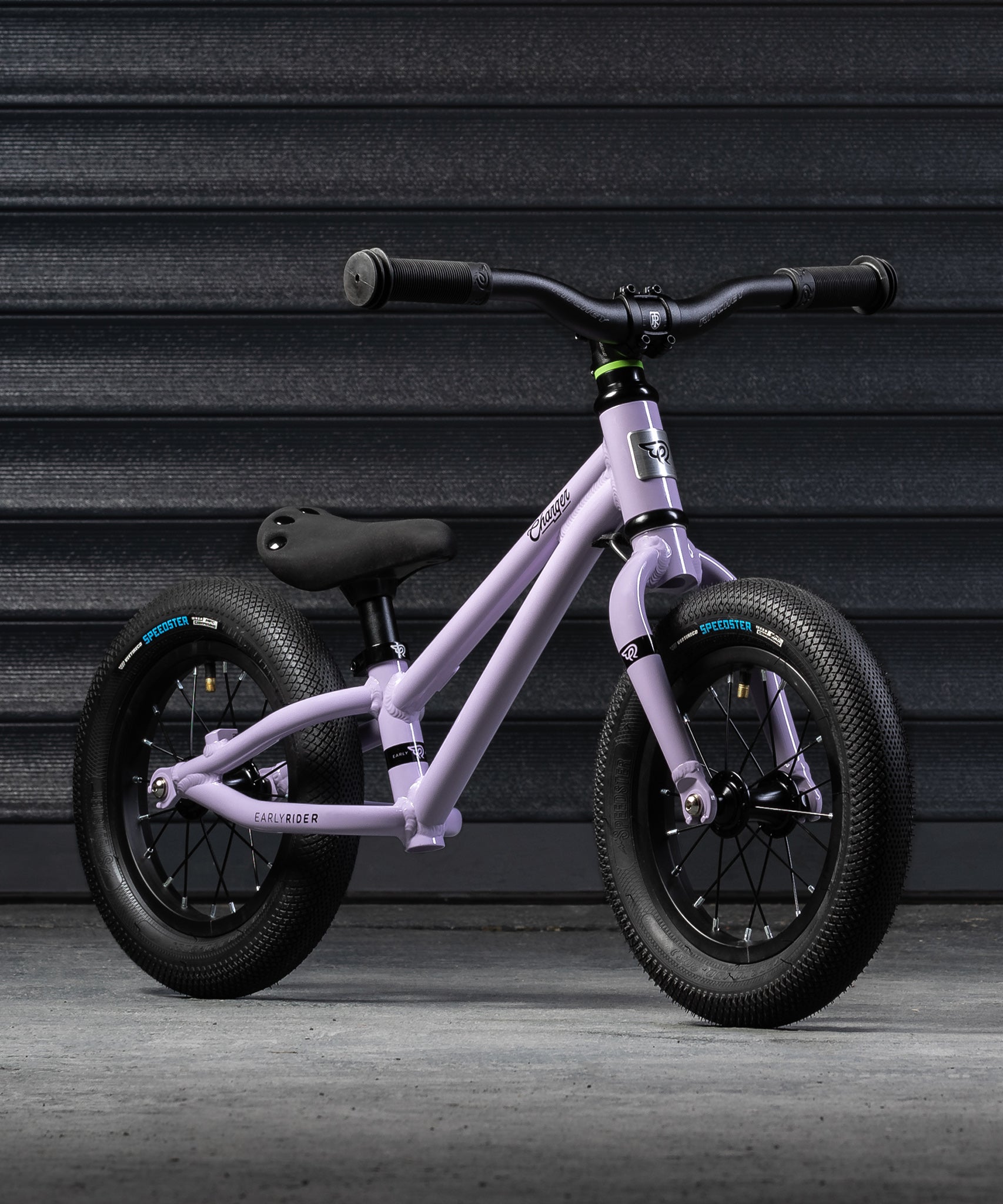 A closer look at the Early Rider Charger Balance Bike - Violet Haze from the front and side, on a grey background