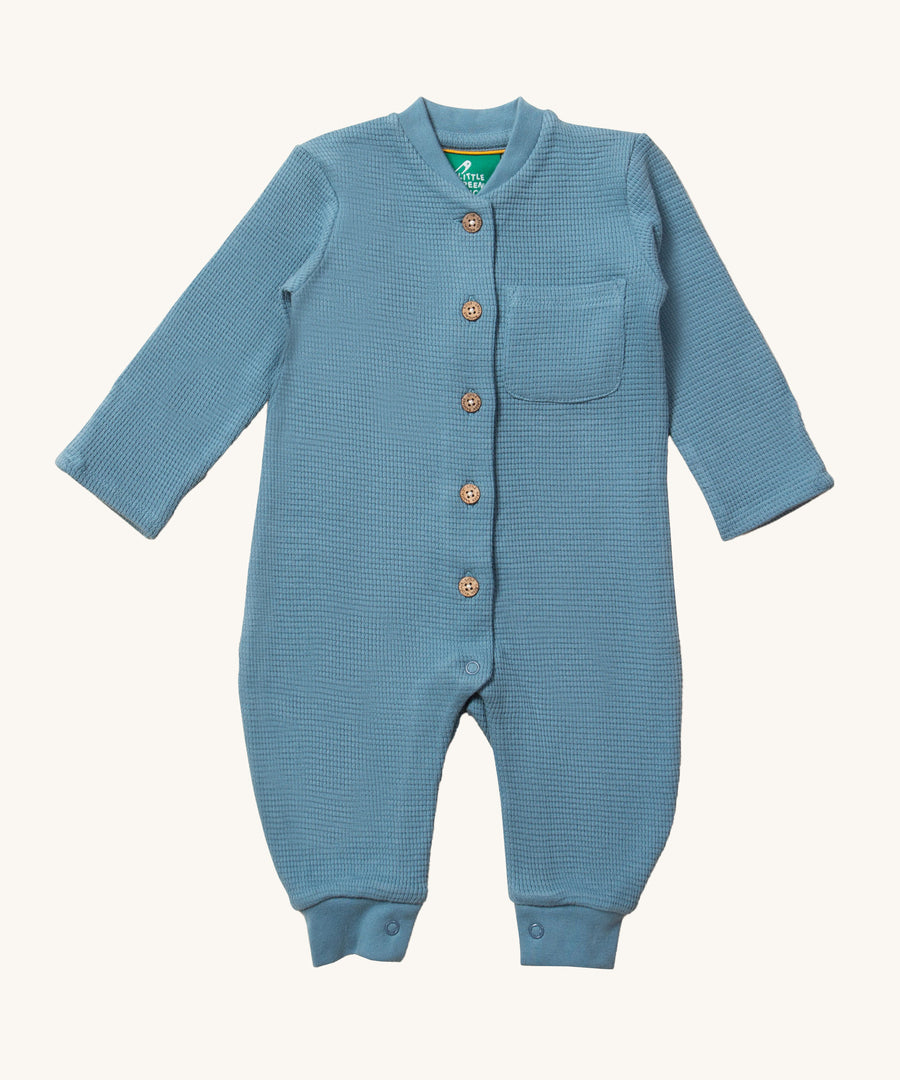 A light blue, waffle texture fabric romper suit, with buttons on the front and a small pocket on the chest