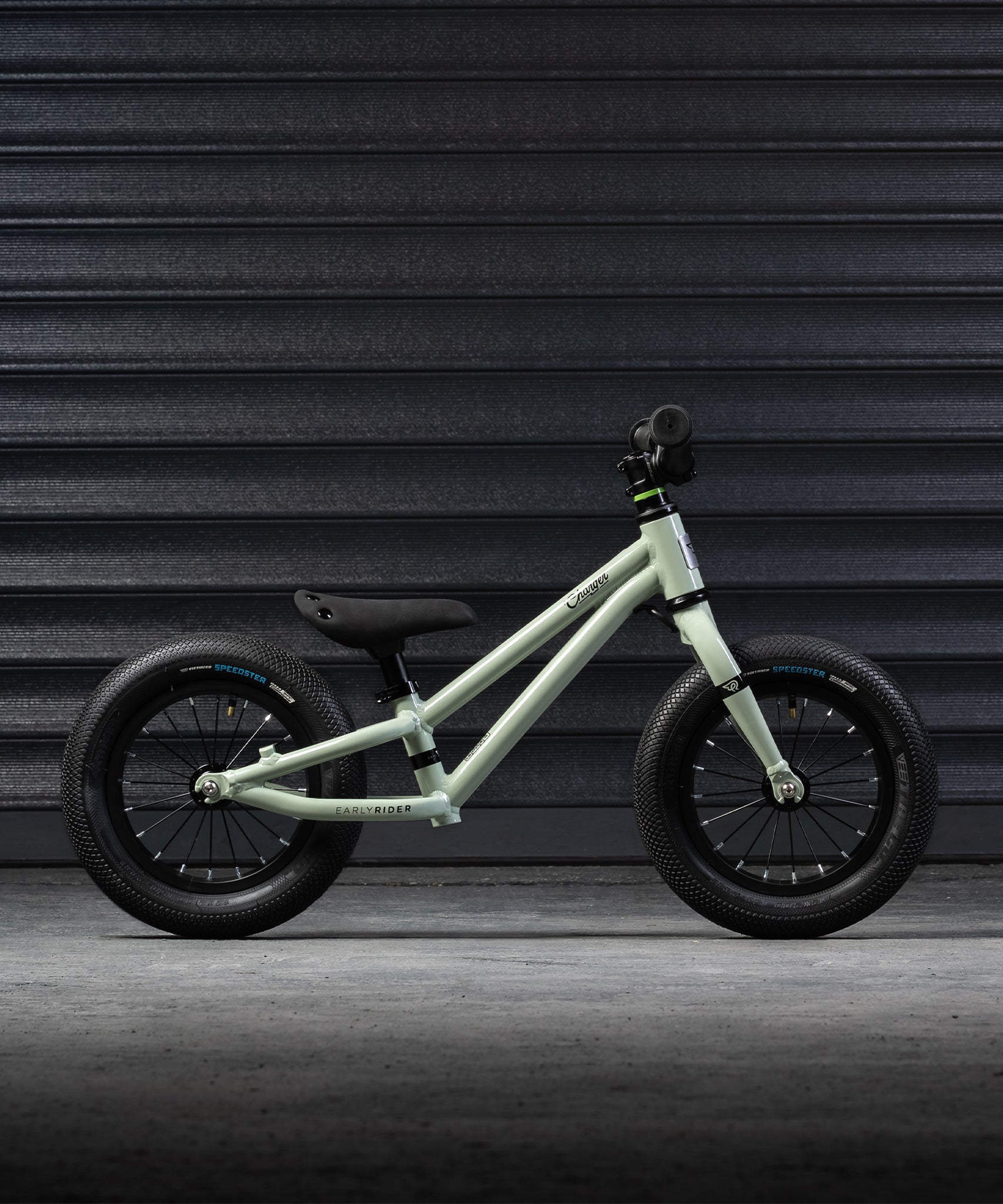 The side of the Early Rider Charger Balance Bike - Sage Green on a grey background