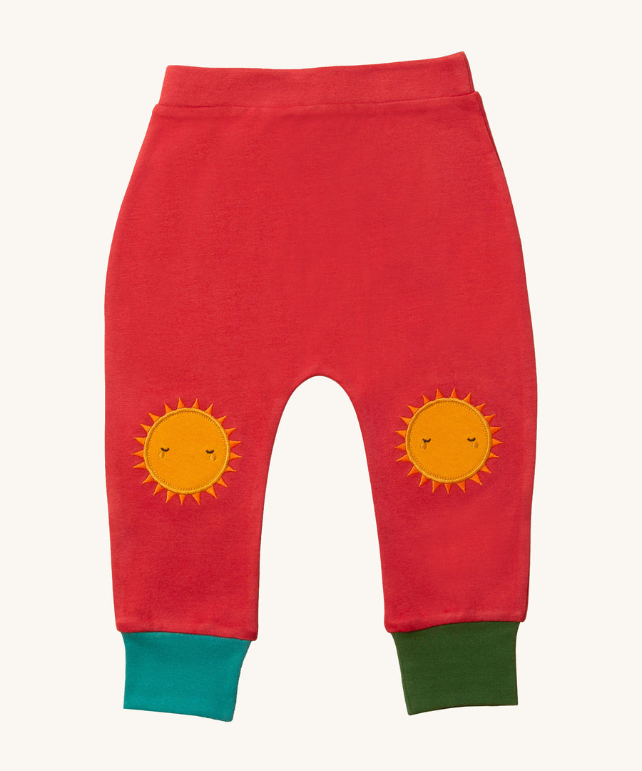 Beautiful and protective sun-shaped knee patches to shield little knees, on red fabric with one green and one turquoise ankle cuff