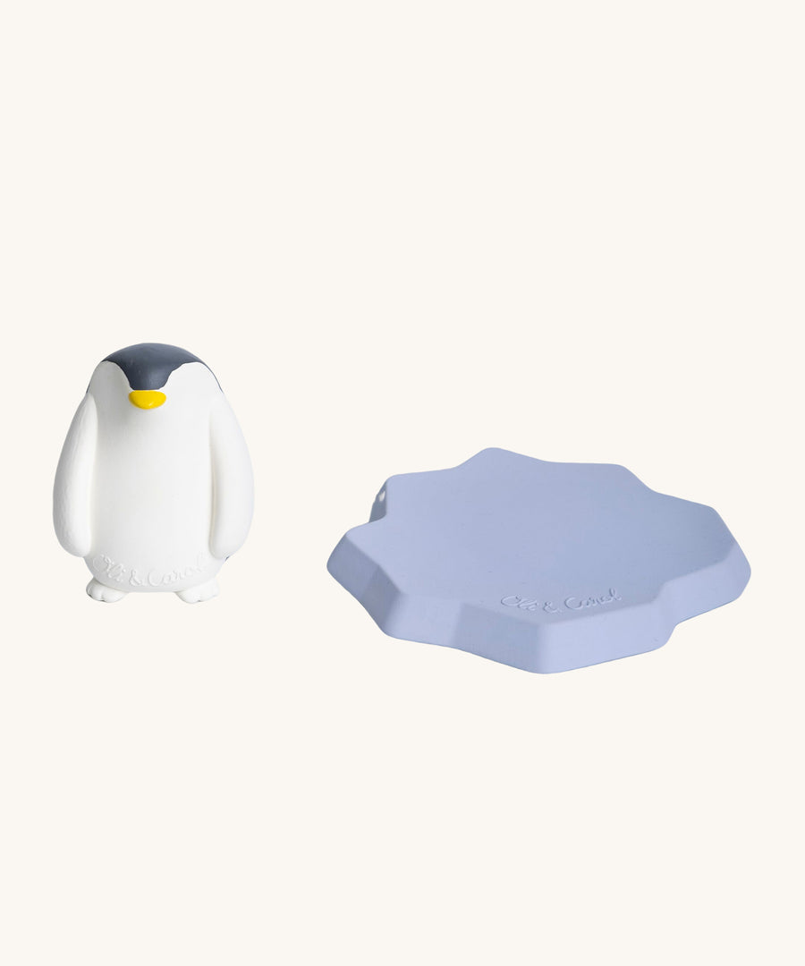 The Oli & Carol Penguin Bath Toy is stood next to its floating iceberg part to the right hand side. The image is on a cream background