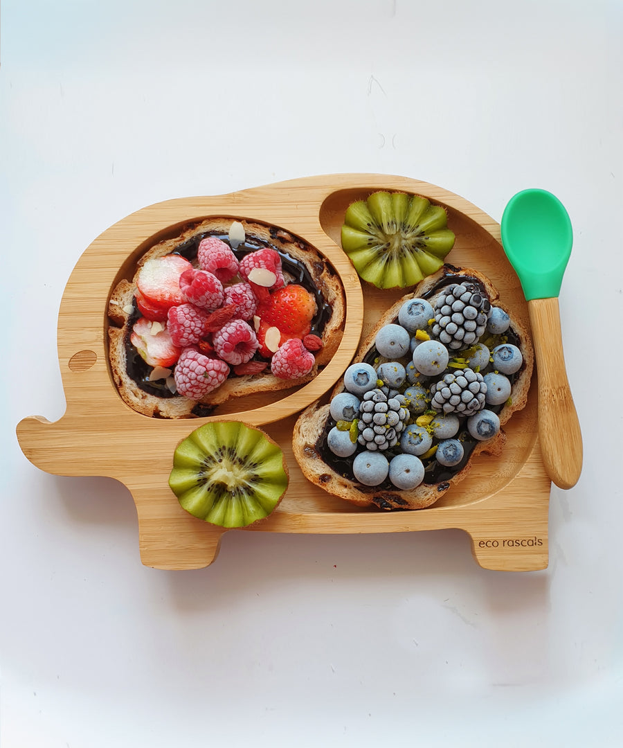 Elephant bamboo baby weaning plate with frozen berries on fruit loaf with a green silicone and bamboo baby spoon.  