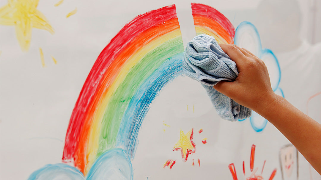 A person erasing a rainbow which was drawn using Kitpas crayons