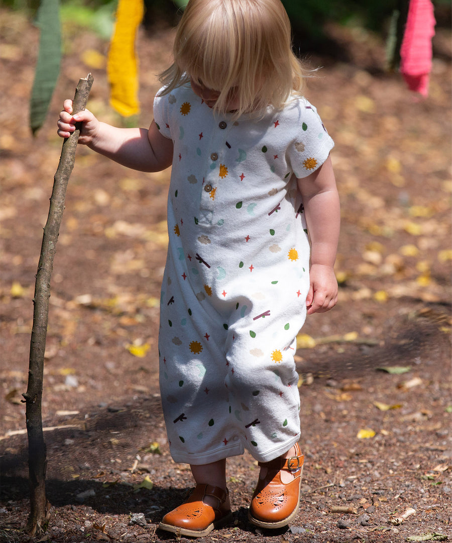 A child playing outside with a stick, wearing the LGR Adventure Baby Towelling Romper