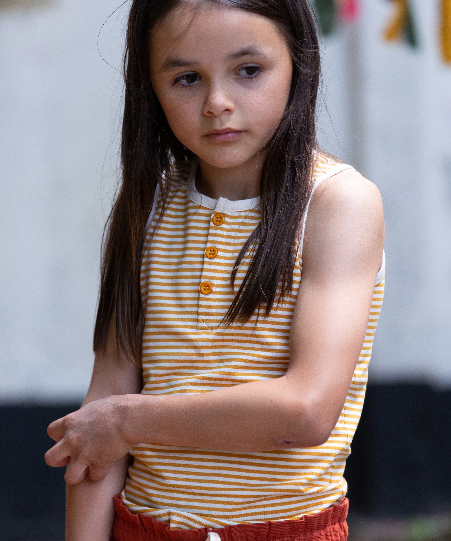 A child wearing the yellow stripe vest top, from the LGR Adventure Organic Vest Set - 3 Pack