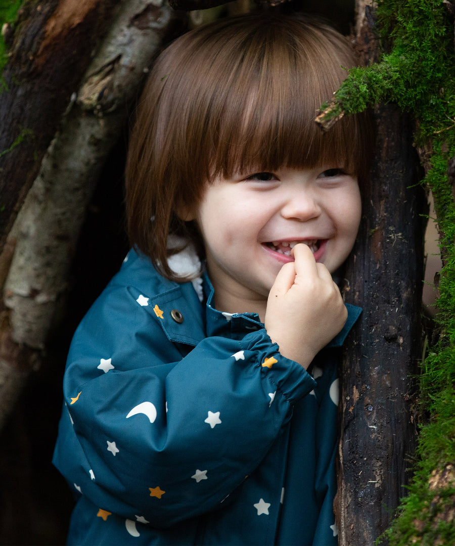 A child happily playing in the woods, wearing the LGR Starry Night Waterproof Winter Suit and showing the elasticated wrist band