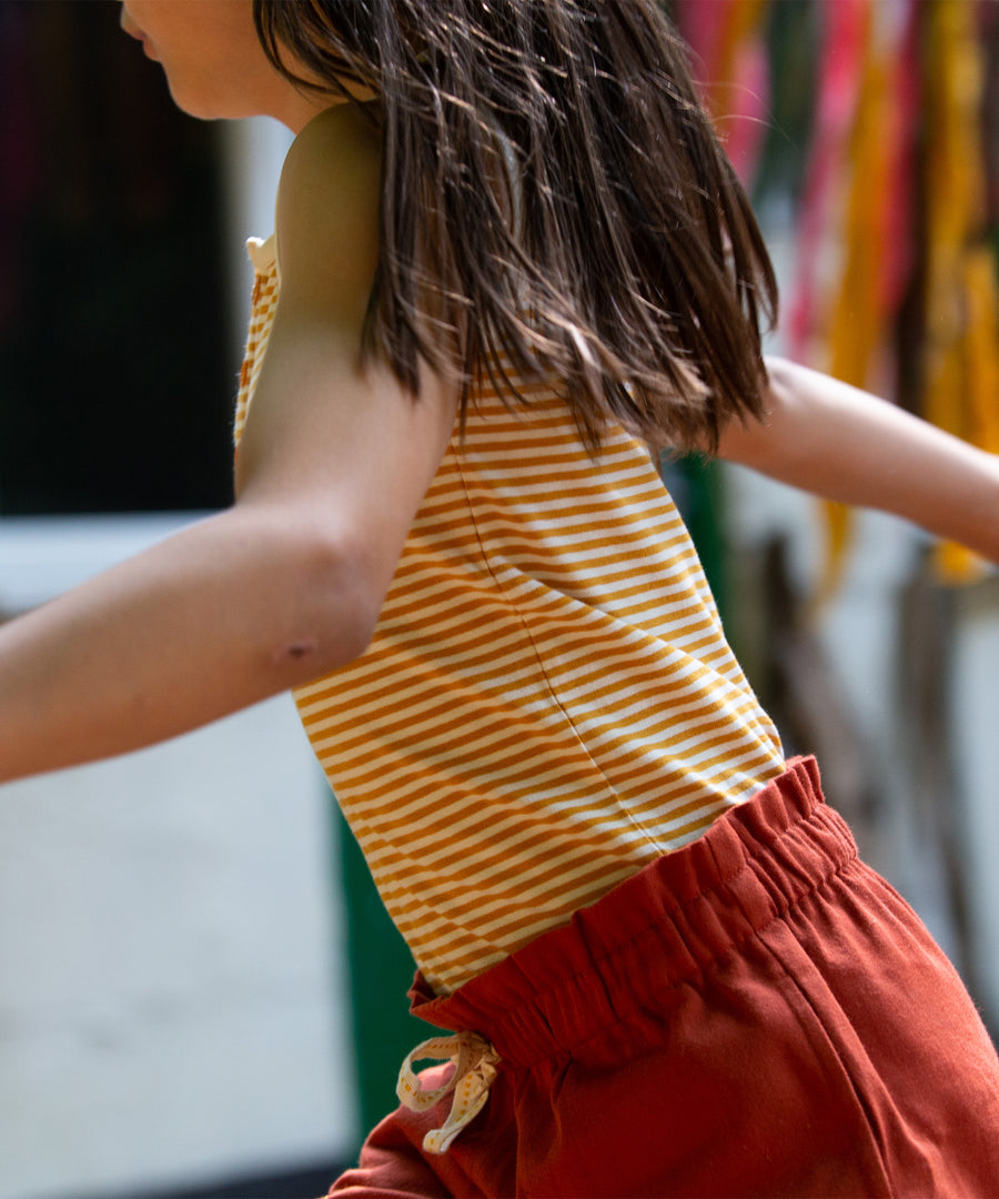 A child wearing the yellow stripe vest top, rom the LGR Adventure Organic Vest Set - 3 Pack