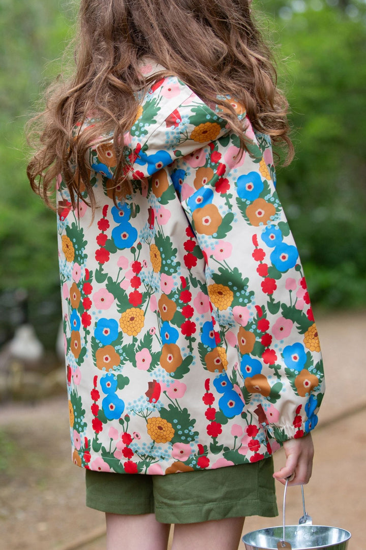 Child wearing floral raincoat from Little Green Radicals in a forest to represent Little Green Radicals rainwear at Babipur.