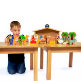 A child playing with the Lanka Kade Deluxe Nativity Set on a wooden table