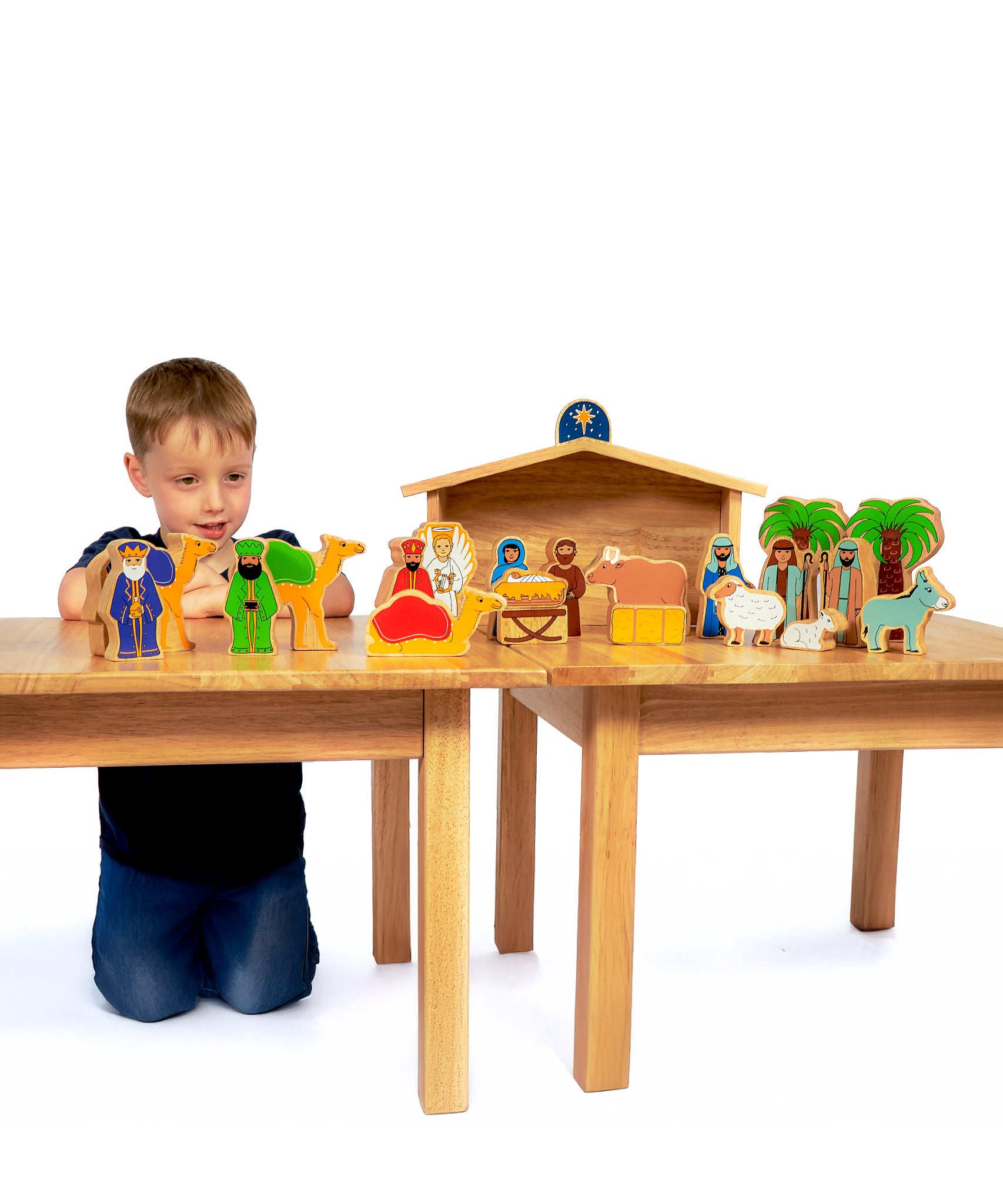 A child playing with the Lanka Kade Deluxe Nativity Set on a wooden table