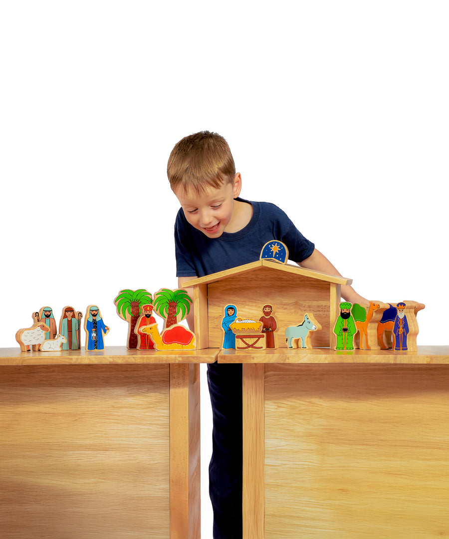 A child playing with the Lanka Kade Deluxe Nativity Set toy on a wooden table