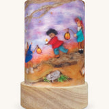 The Lantern Walk illustration by Het Wol Feetje sat in a Toverlux Magic Lantern base, on a cream background