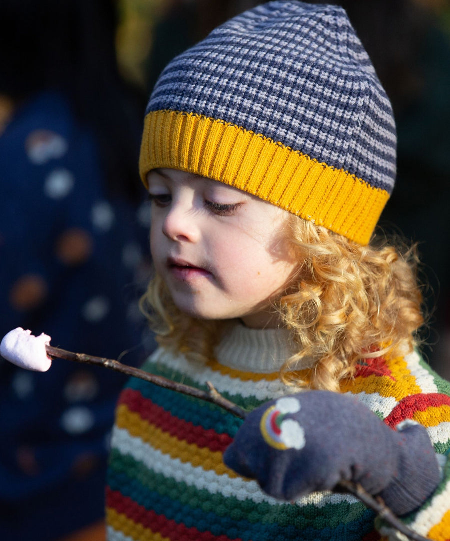 A child eating a roasted marshmallow off a stick, wearing the Dreamy Blue Knitted Beanie Hat