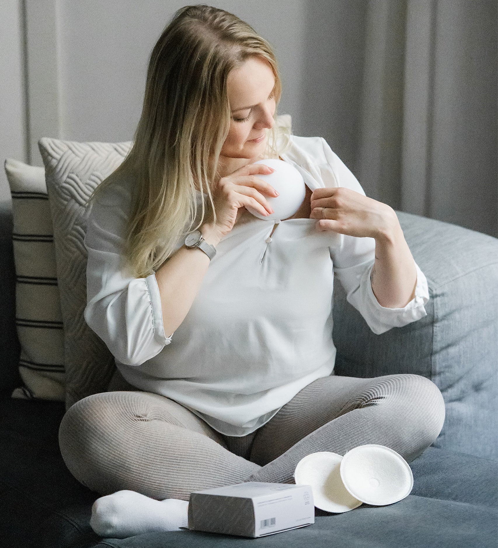 A person putting on the Lola & Lykke Curved Bamboo Nursing Pads, under their top