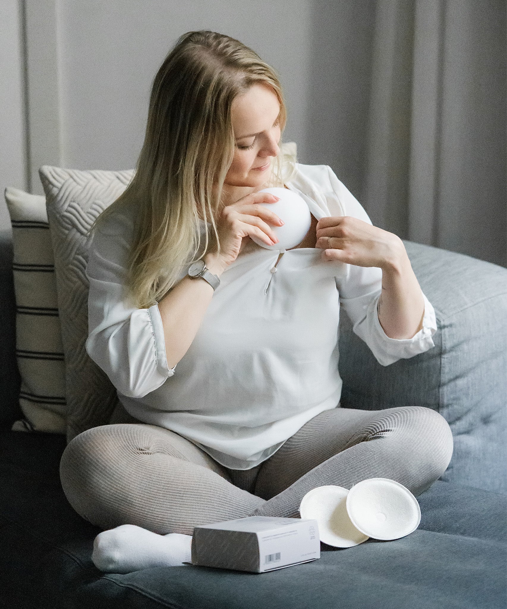 A person putting on the Lola & Lykke Curved Bamboo Nursing Pads, under their top