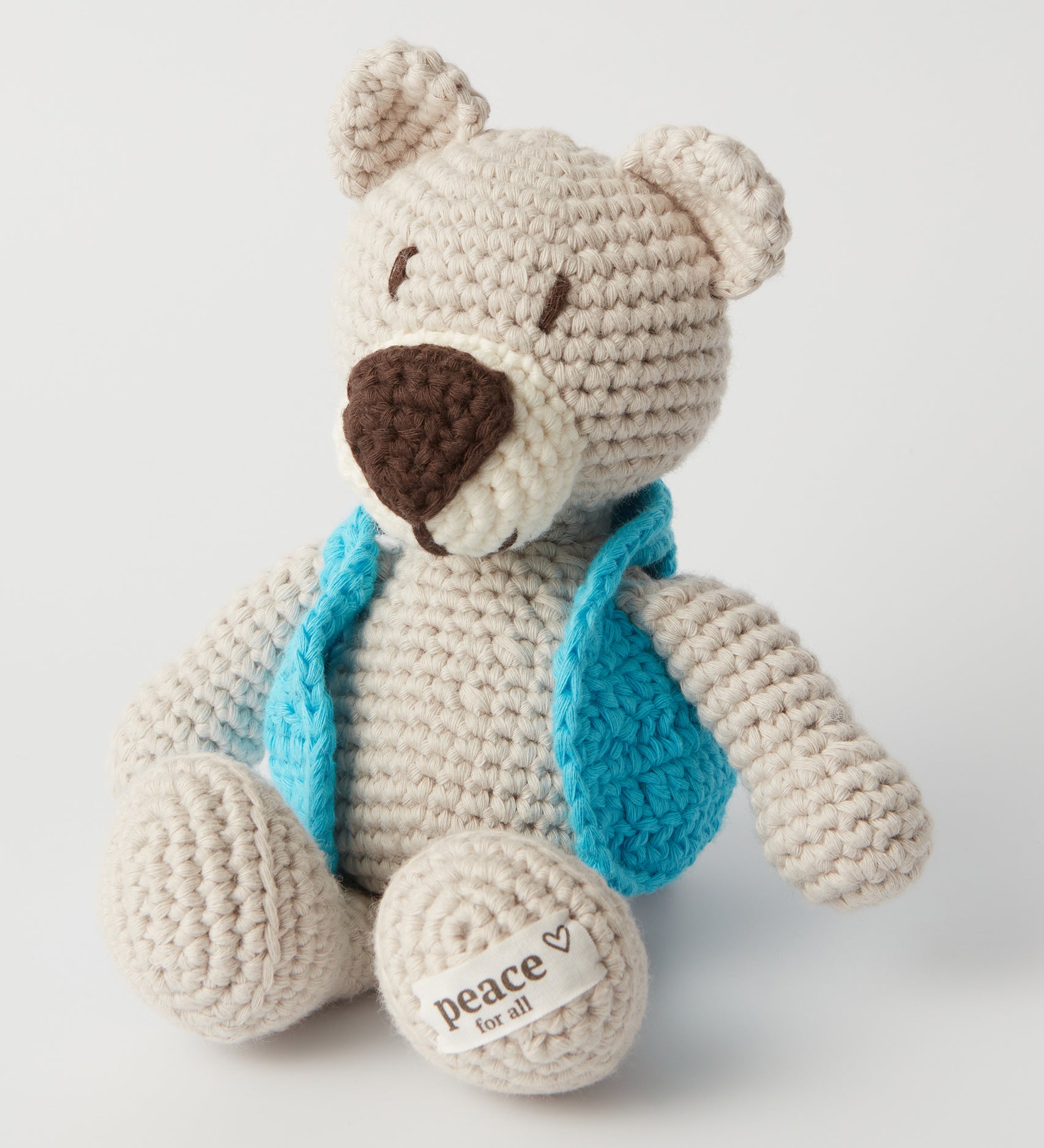 The MADE51 Peace Bear sat up, wearing a little light blue jacket and a Peace For All label on its foot