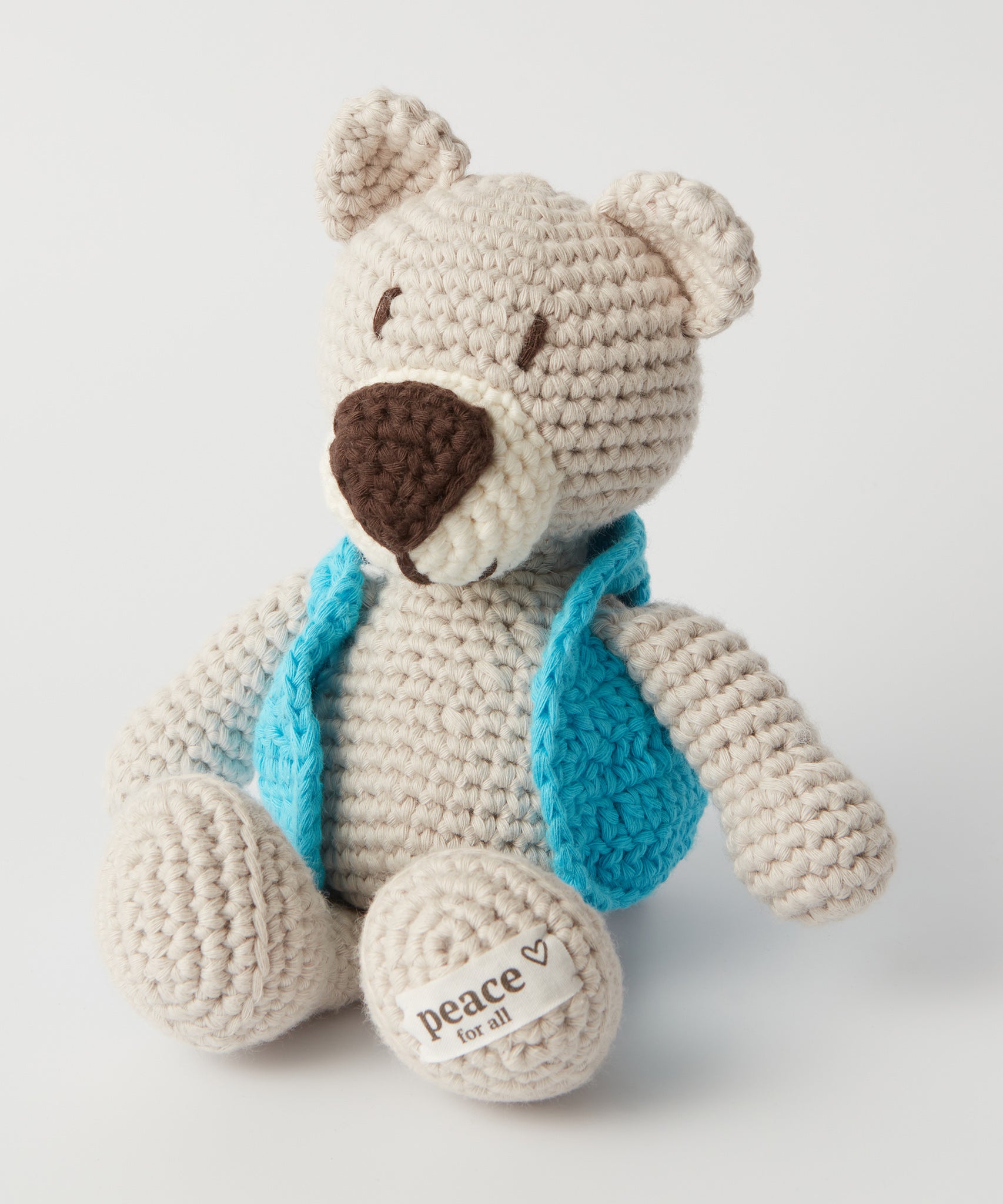 The MADE51 Peace Bear sat up, wearing a little light blue jacket and a Peace For All label on its foot