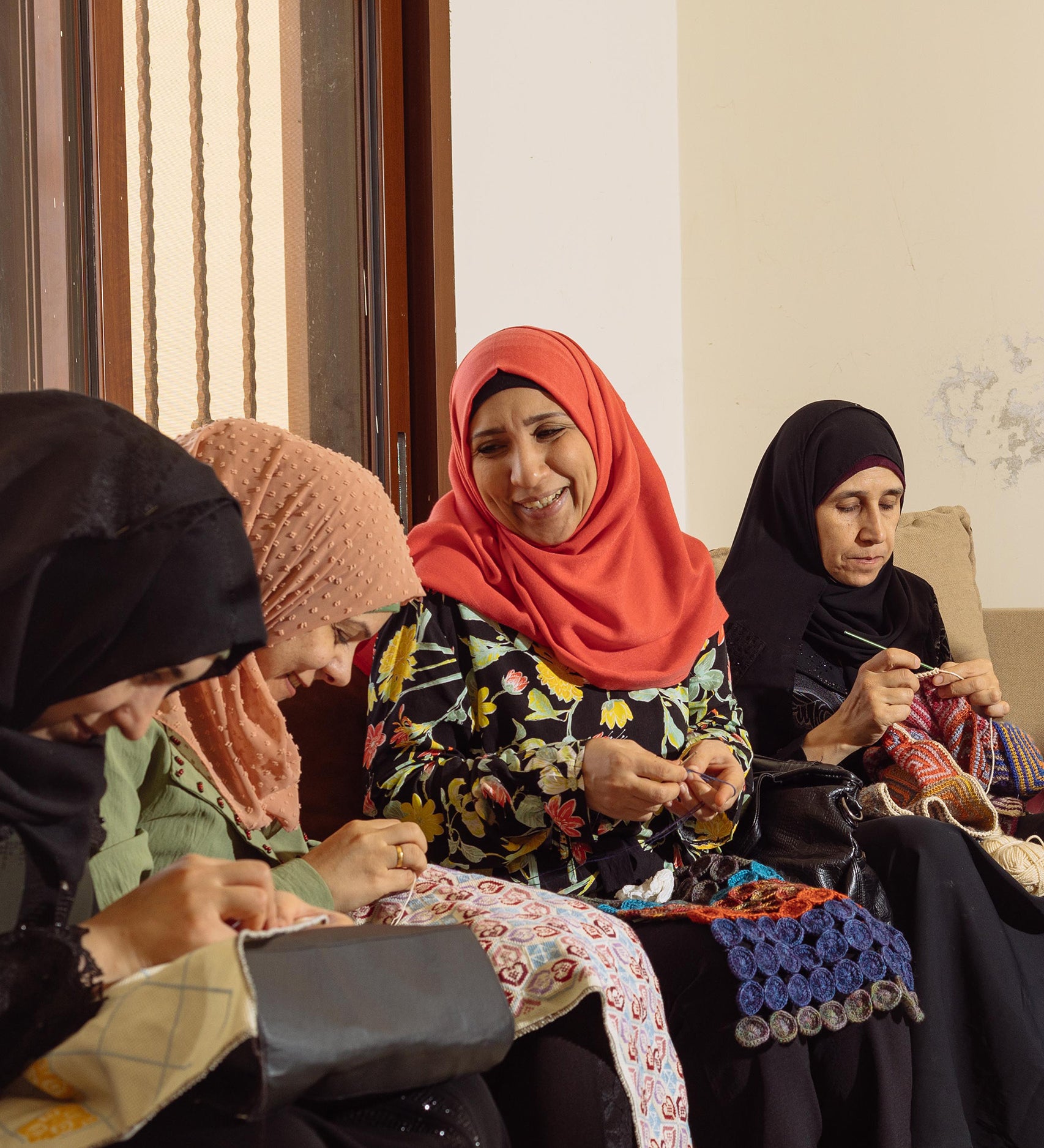 Syrian Refugees sitting together hand-making beautiful blankets, pouches and bags