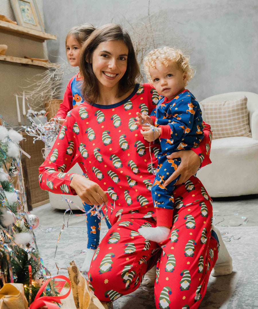 A woman wearing a Maxomorra Swedish Santa Adult Long Sleeve Pyjama Set holding a small child that is wearing a reindeer print rompersuit. 