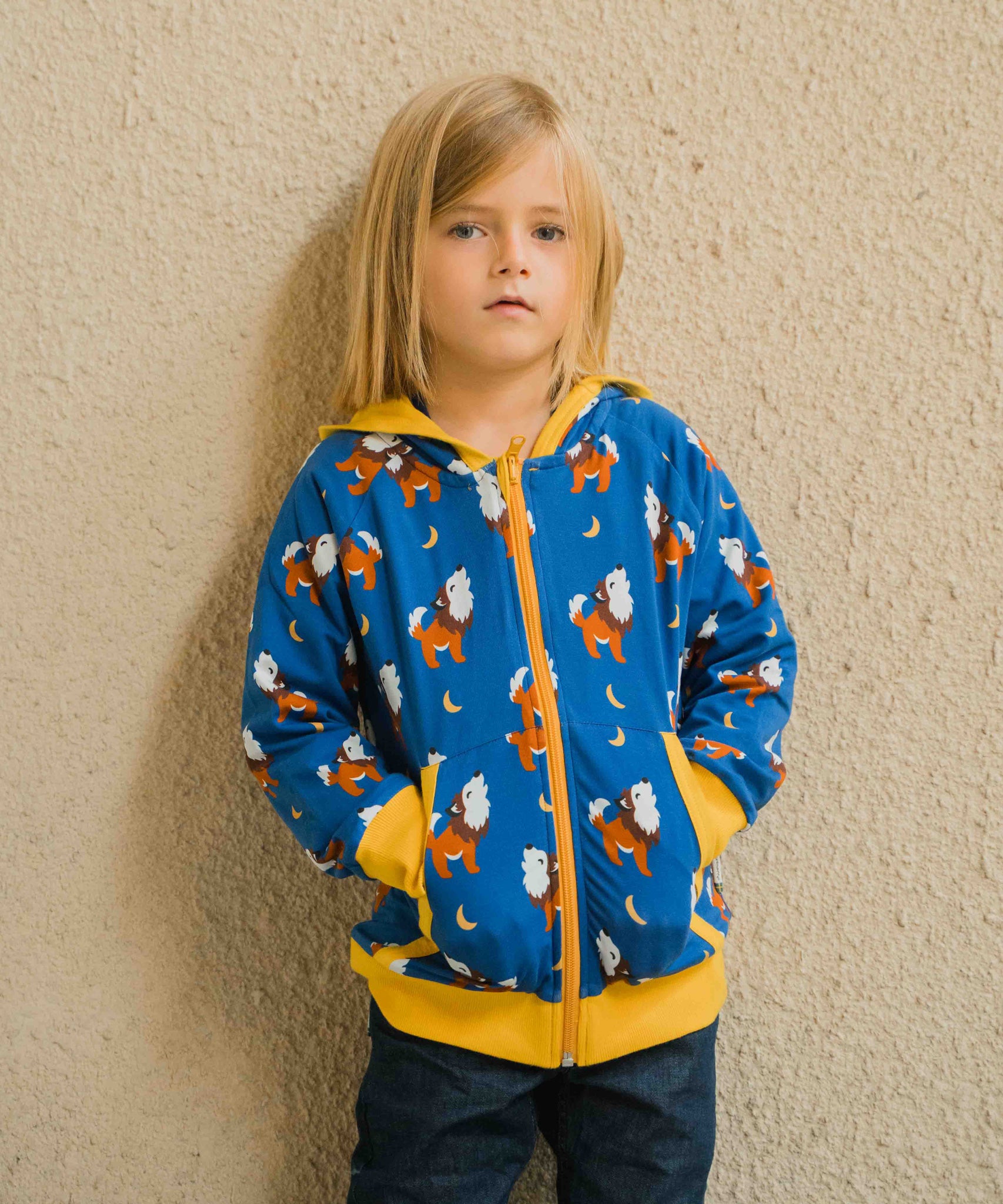 A child wearing a Maxomorra Wolf Reversible Zip Hoodie. The child has his hands in his pockets. 