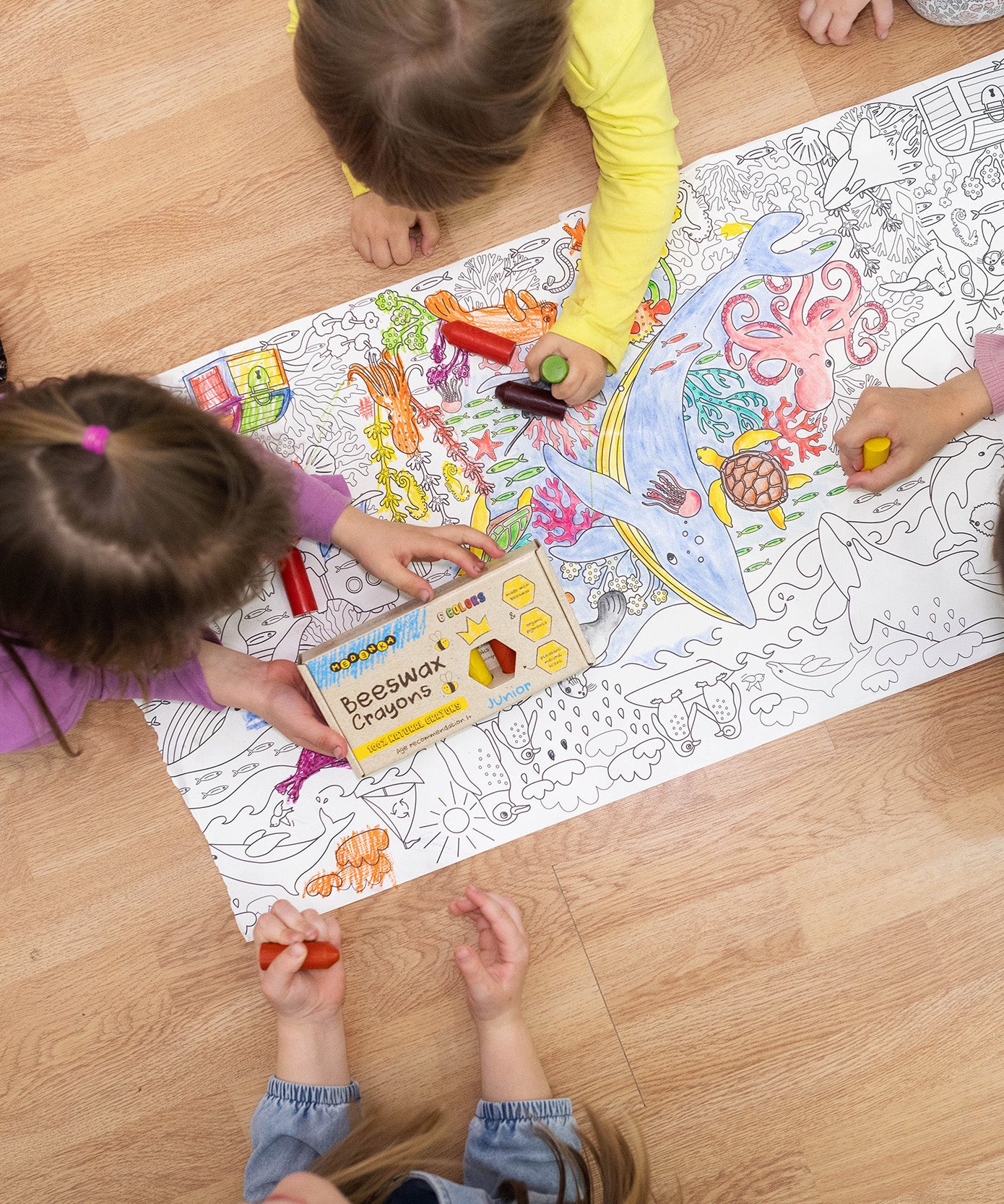 Children colouring in a large ocean scene on the floor, using the Medenka junior beeswax crayons.