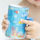 A baby holding a soapy box of Medenka beeswax bath crayons in the bath. 