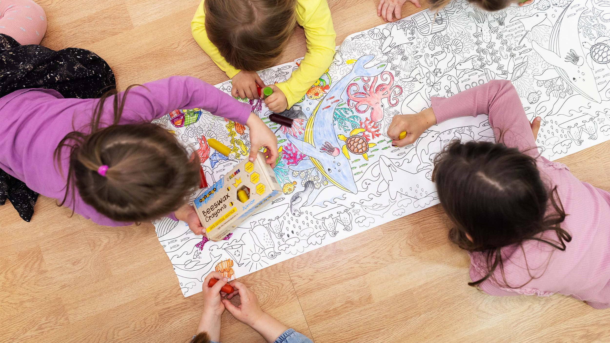 Children colouring in a large page on the floor, using Medenka beeswax crayons.