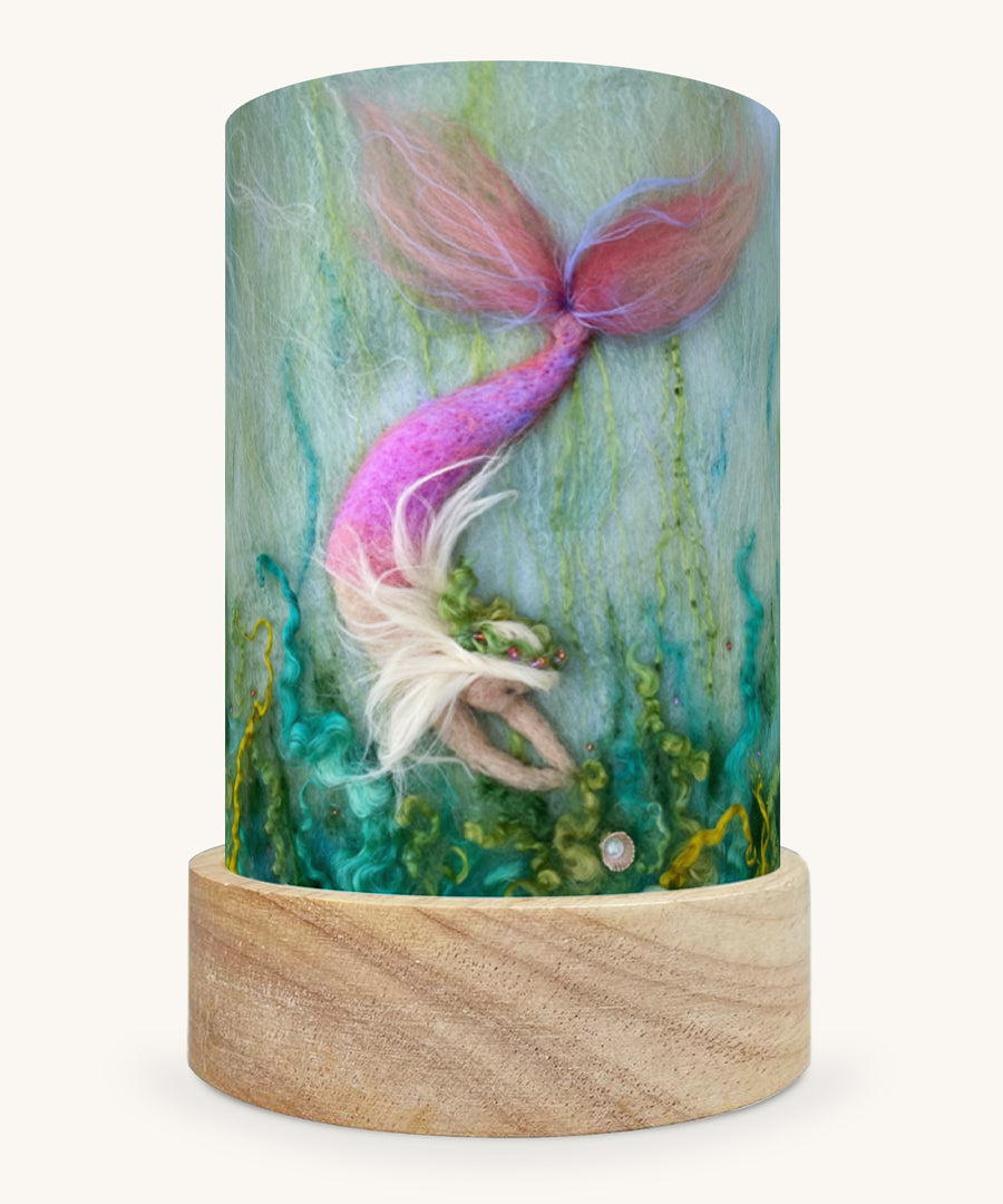 The Mermaid Treasures illustration by Het Wol Feetje sat in a Toverlux Magic Lantern base, on a cream background