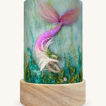 The Mermaid Treasures illustration by Het Wol Feetje sat in a Toverlux Magic Lantern base, on a cream background