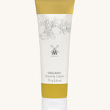 MÜHLE Organic Shaving Cream in a mustard and white tube with delicate olive branch design on the packaging and the Muhle logo in the middle. On a cream background