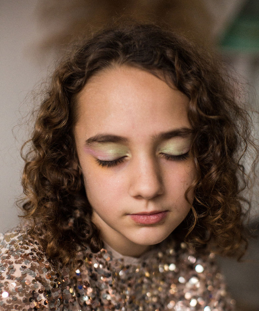 A child wearing the Namaki Natural Eyeshadow in Fawn colours. The colours on the child's eyelids are green, pink and gold