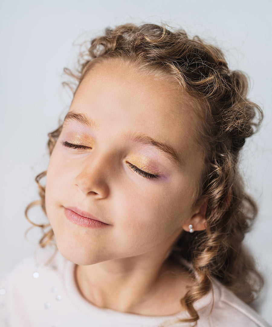 A child wearing the eye shadow from the Namaki Natural Eyeshadow Pallet - Owl. The colours on the childs eye lids are gold, pink and purple