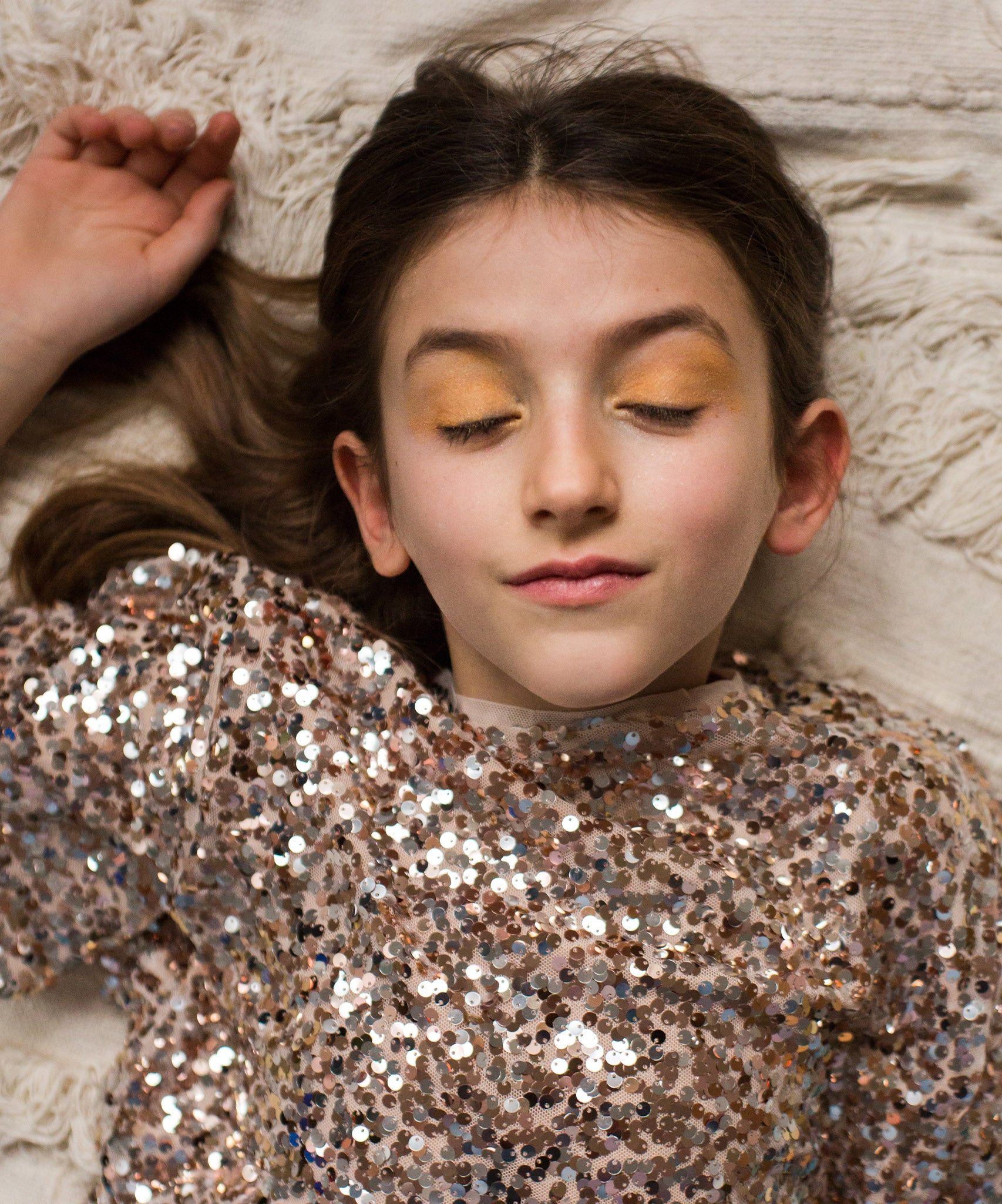 A child wearing the gold makeup from the Namaki Gold Fox Sparkling Pouch, whilst lying down with their eyes closed 