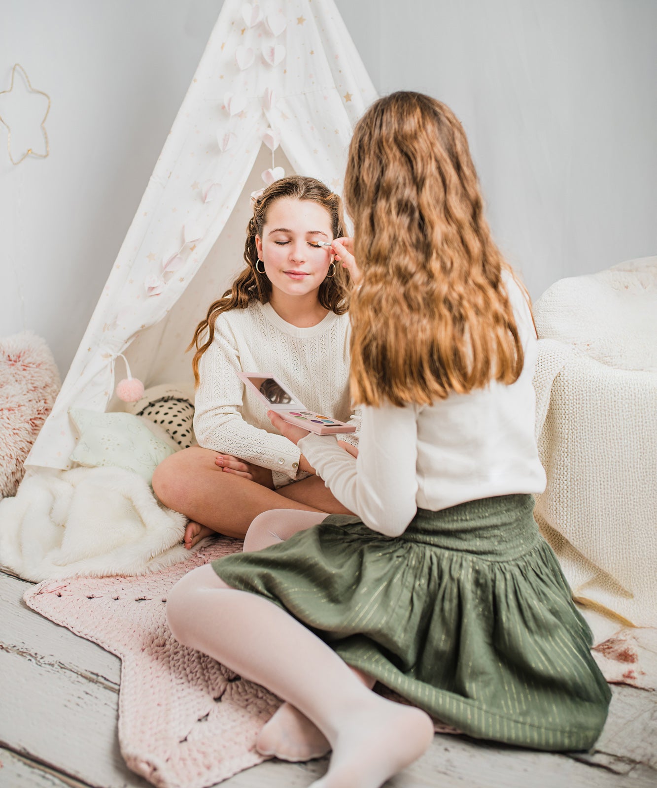 Two children sitting in a bedrom putting on eye shadow from the Namaki Natural Eyeshadow Pallet