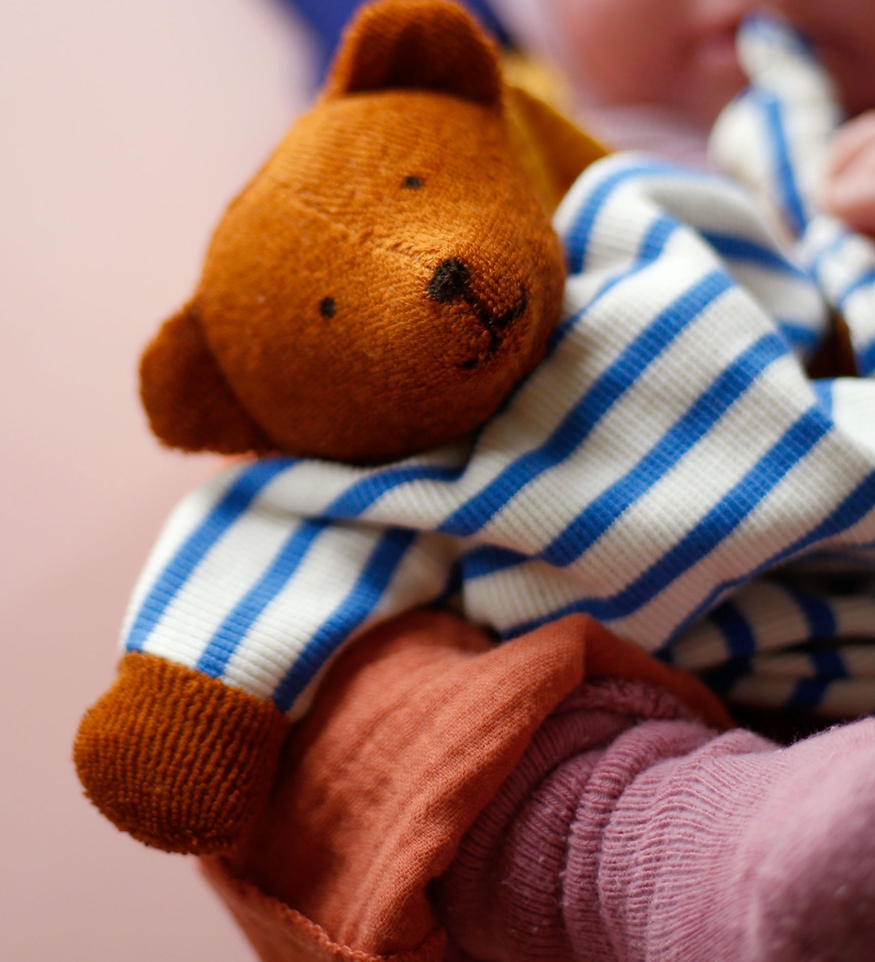 A beautifully handmade teddy bear comforter toy, the Nanchen Baby Comforter - Bear has brown face and  hands, and a blue and white stripe body